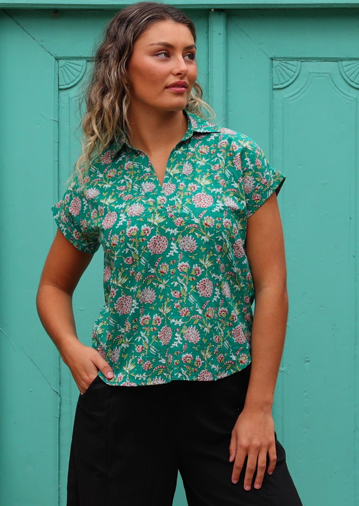 Model poses in cotton short sleeve short with rolled cuff in floral print on a jade green base