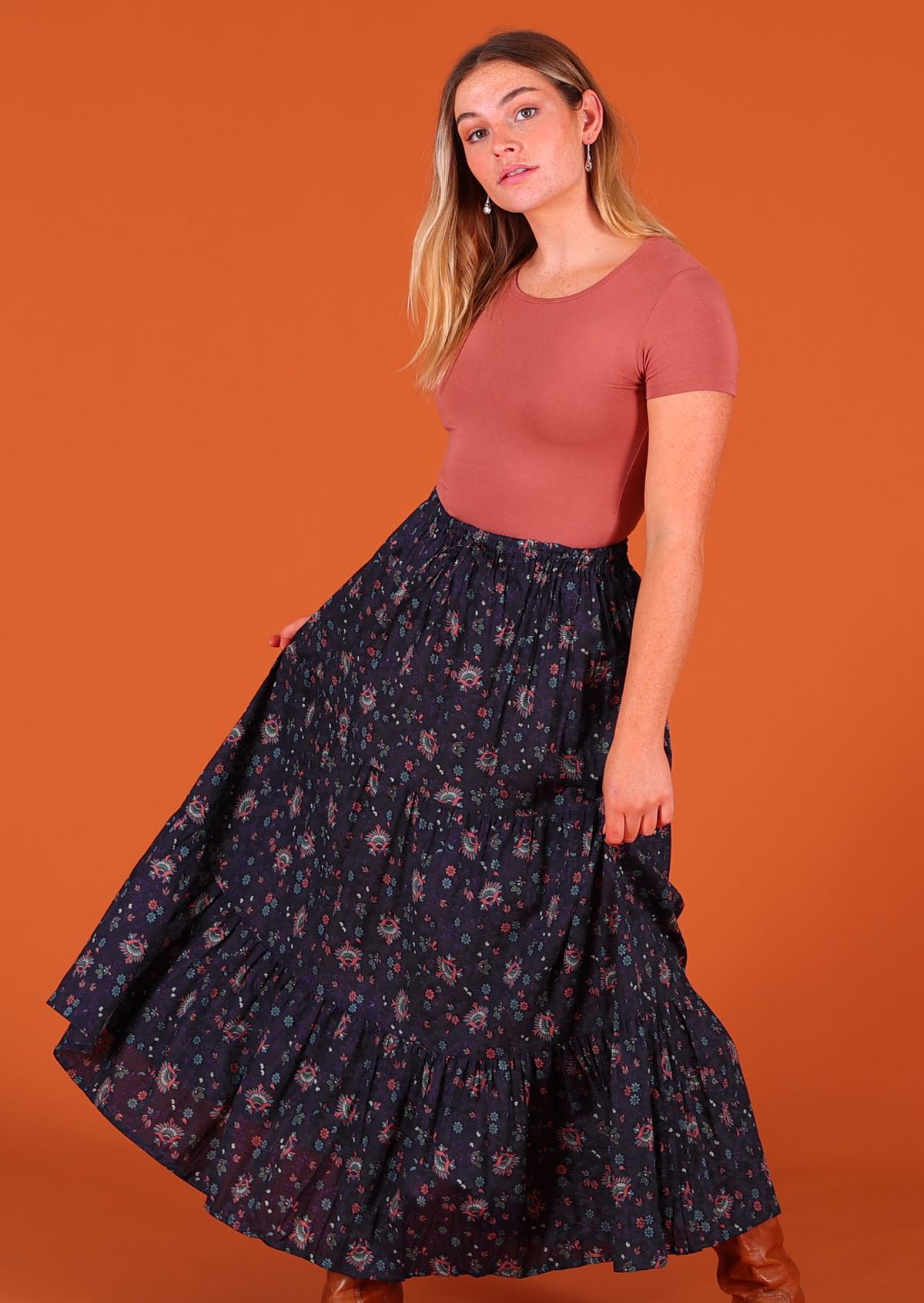 Model standing wearing dark Purple 100 percent cotton Indian floral printed three tiered maxi skirt