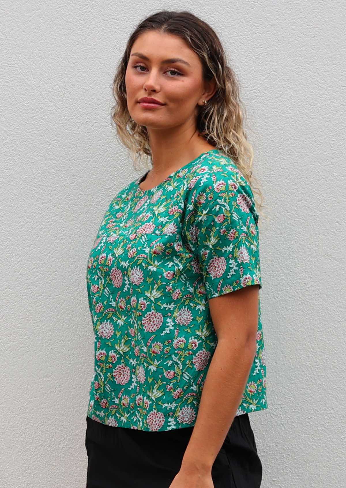 Woman wears cotton short sleeve relaxed fit floral top with jade green base