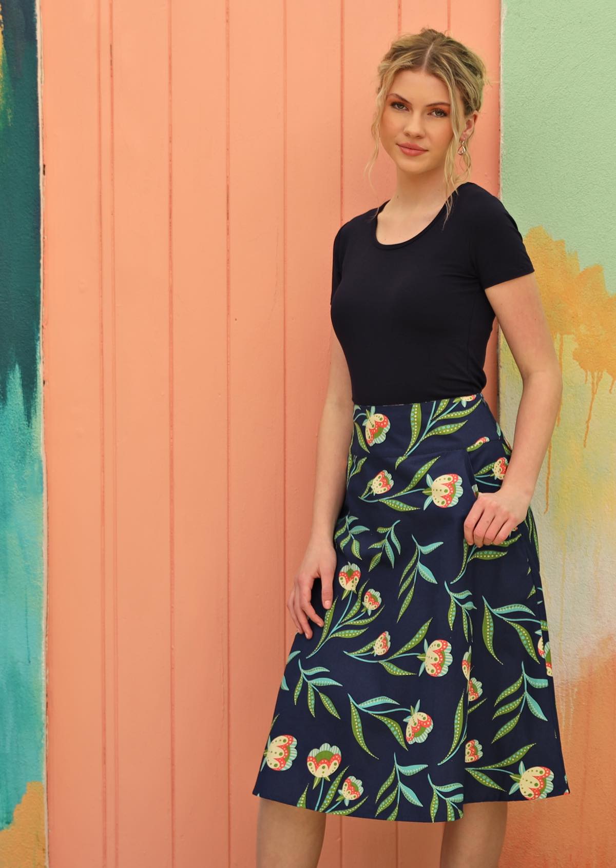 Women wears navy skirt with a green floral pattern.