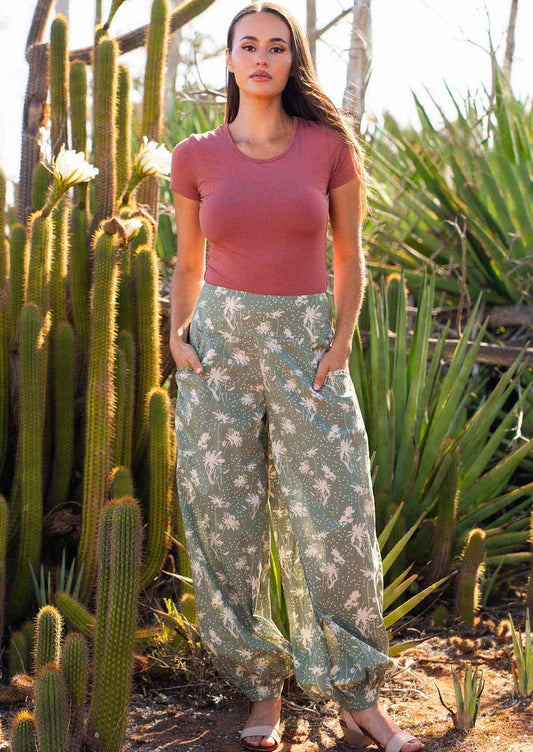 Model poses in pale green cotton harem pants with buttoned ankle and pockets, and a stretch rayon top in dusty rose