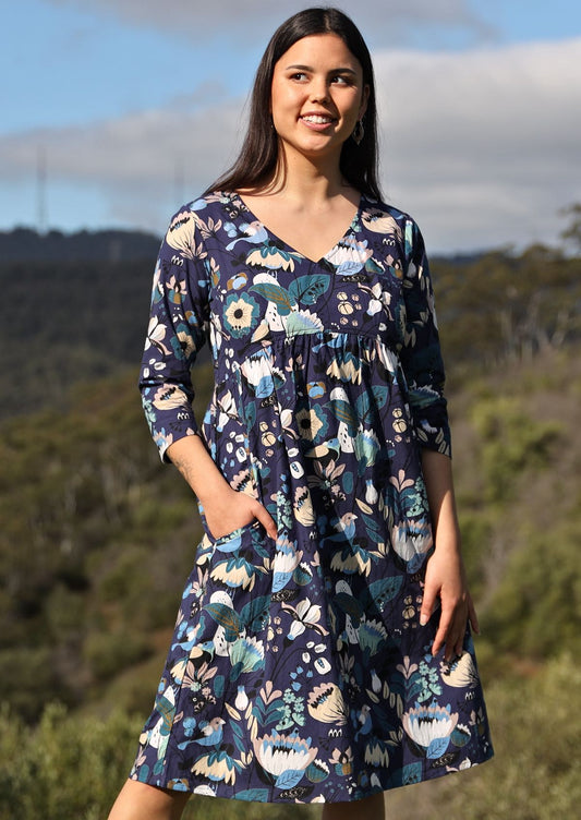 April Dress v-neck 3/4 sleeve empire waistline gathering under waistline pockets knee length 100% cotton navy background blue toned floral and bird print | Karma East Australia