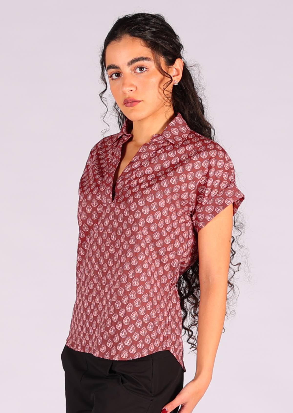 Model wears a dark terracotta relaxed fit top with a v neckline made from 100% cotton. 