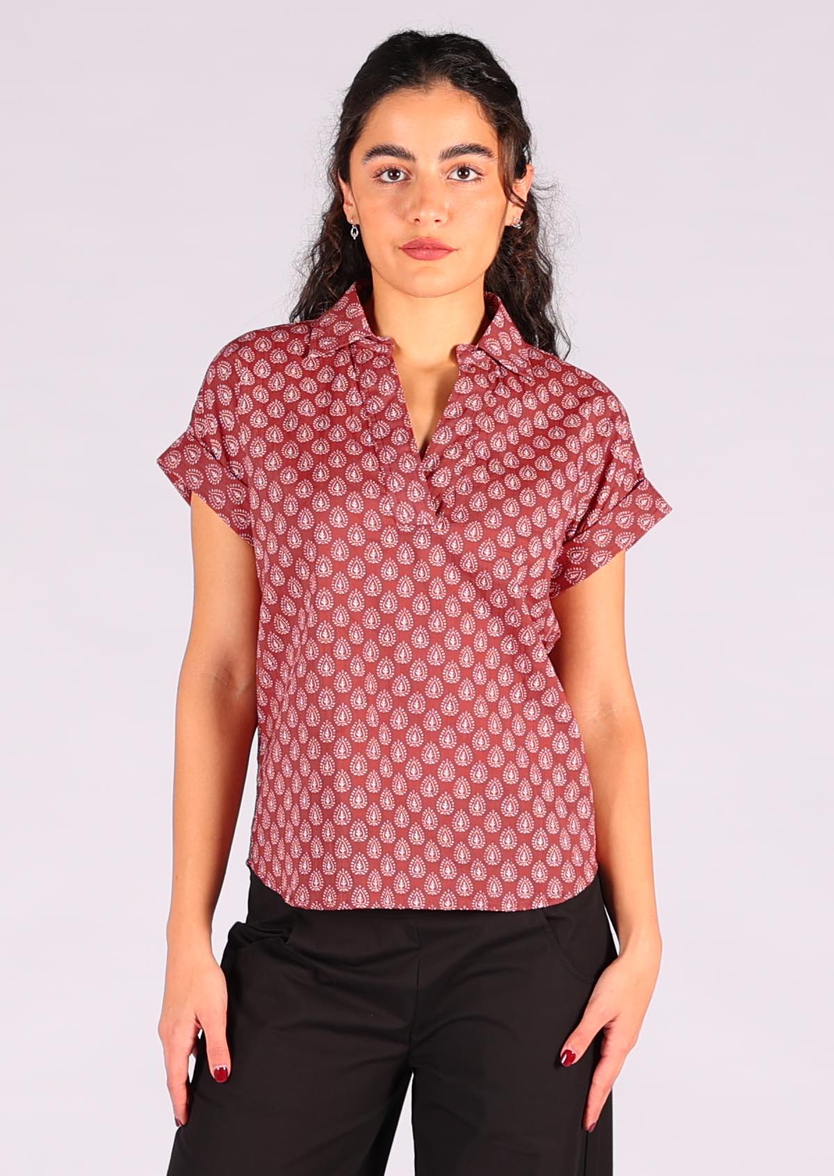 Woman standing and wearing a relaxed fit cotton top with collar in a dark terracotta shade