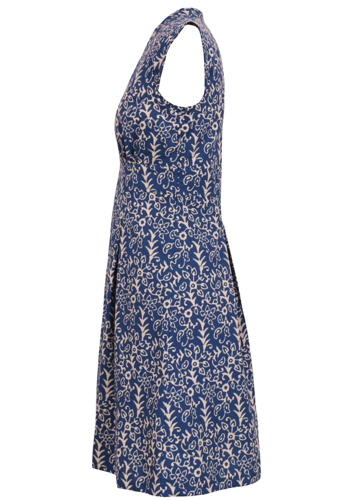 Side mannequin photo of retro style cotton dress with box pleats, cap sleeves, V-neckline and side zip