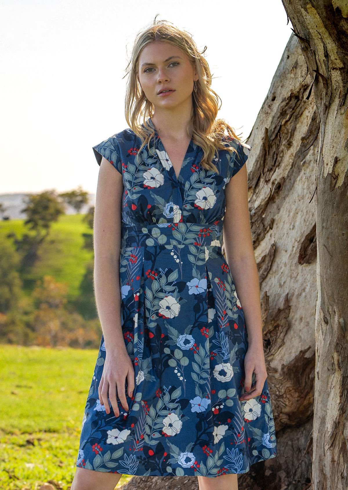 Model wears retro style cotton dress with modest V-neckline and cap sleeves in blue floral print