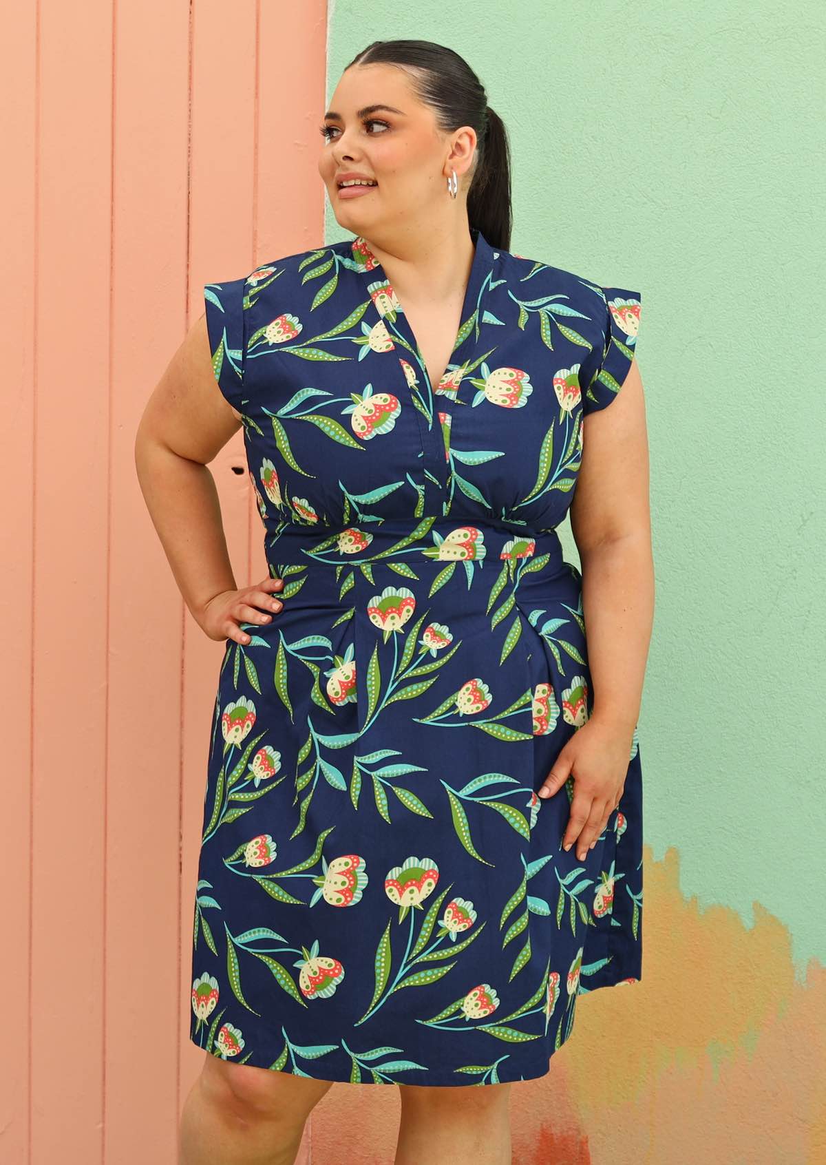 Curve model wears navy dress with cap sleeves. 