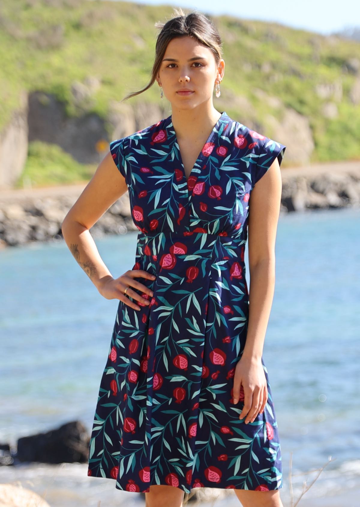 Model wears 100% cotton classic style knee length dress with a blue and red fruit pattern. The V neck dress has an a-line skirt, cap sleeves and a side zip.