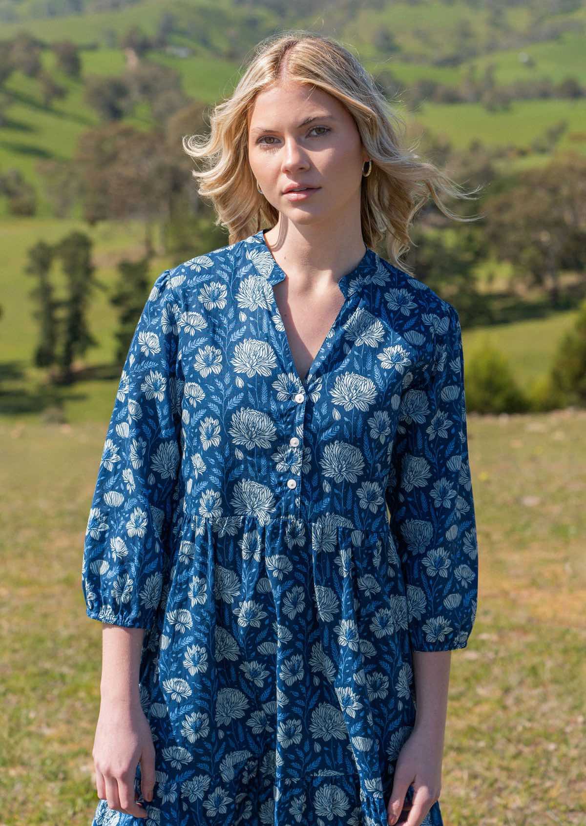 Close up of model in cotton maxi dress with V-neckline and mandarin collar, three shell buttons in front of bodice