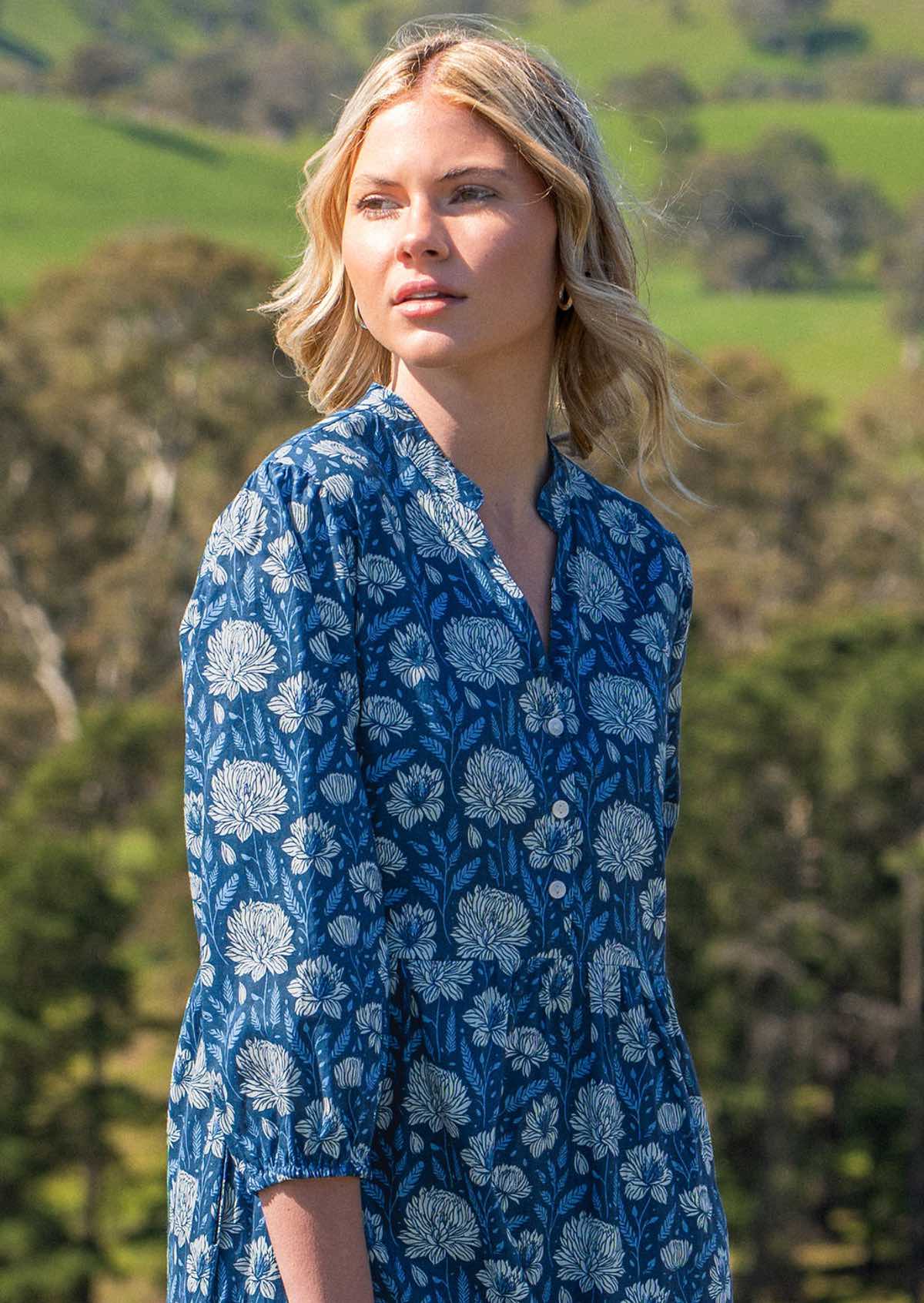 Model looks over shoulder in blue floral cotton maxi dress with 3/4 sleeves