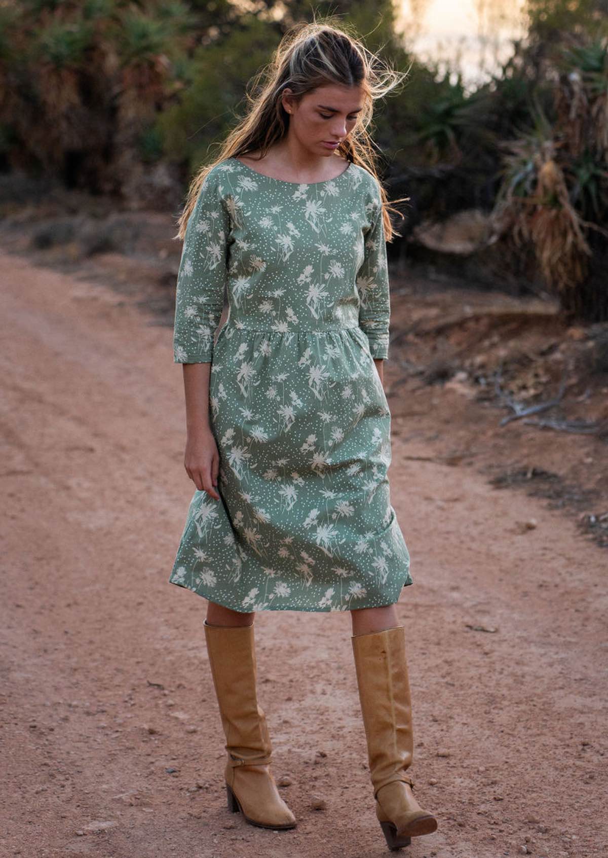 Woman wears pale green cotton over the knee length dress with 3/4 sleeves and boat neckline