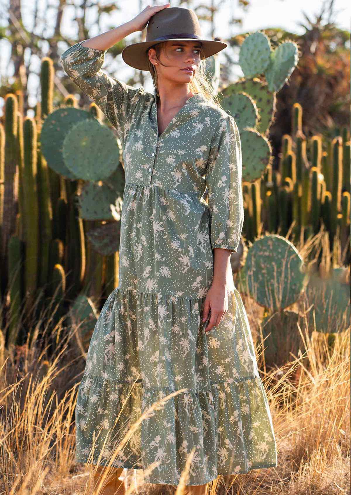 Woman holds hat in cotton tiered maxi dress with 3/4 sleeves and buttoned bodice