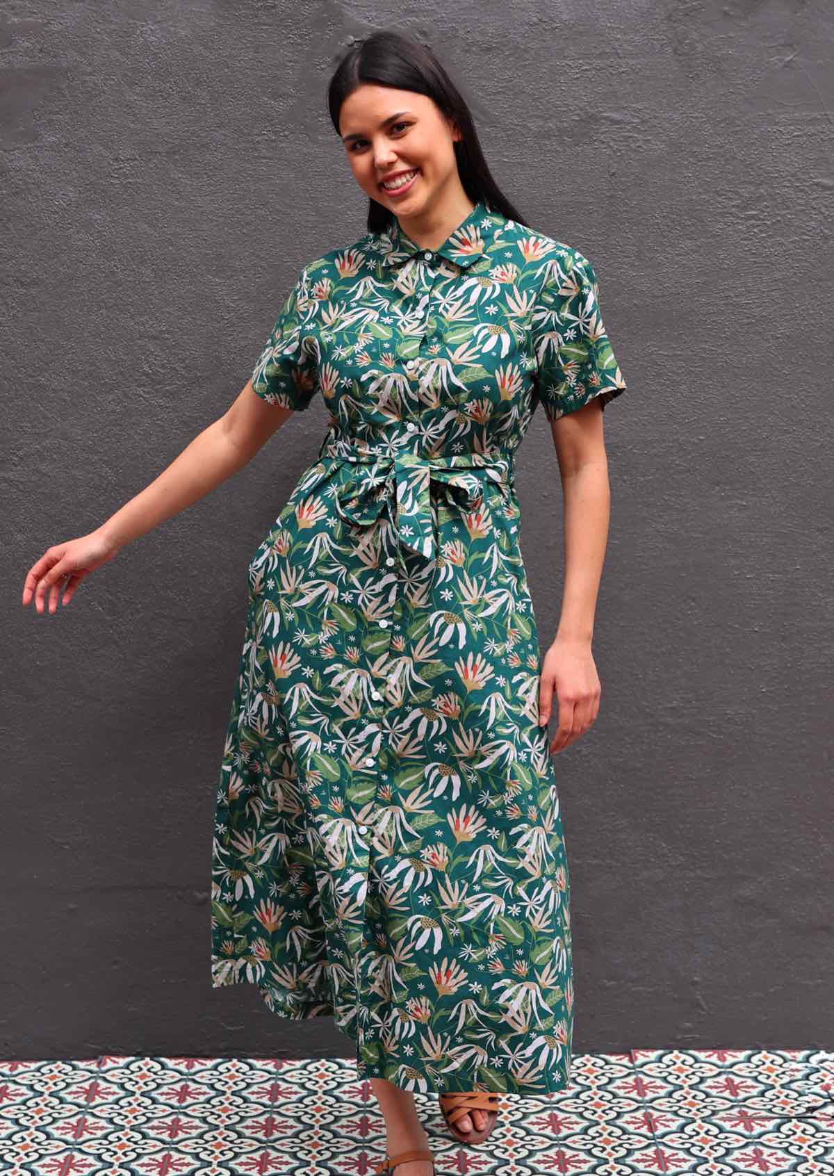 Woman with dark hair wearing 100% cotton green floral shirt dress, buttons up front