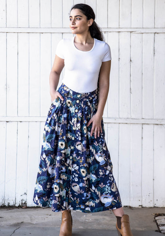 Model poses in cotton midi length skirt with florals and birds in the blue print