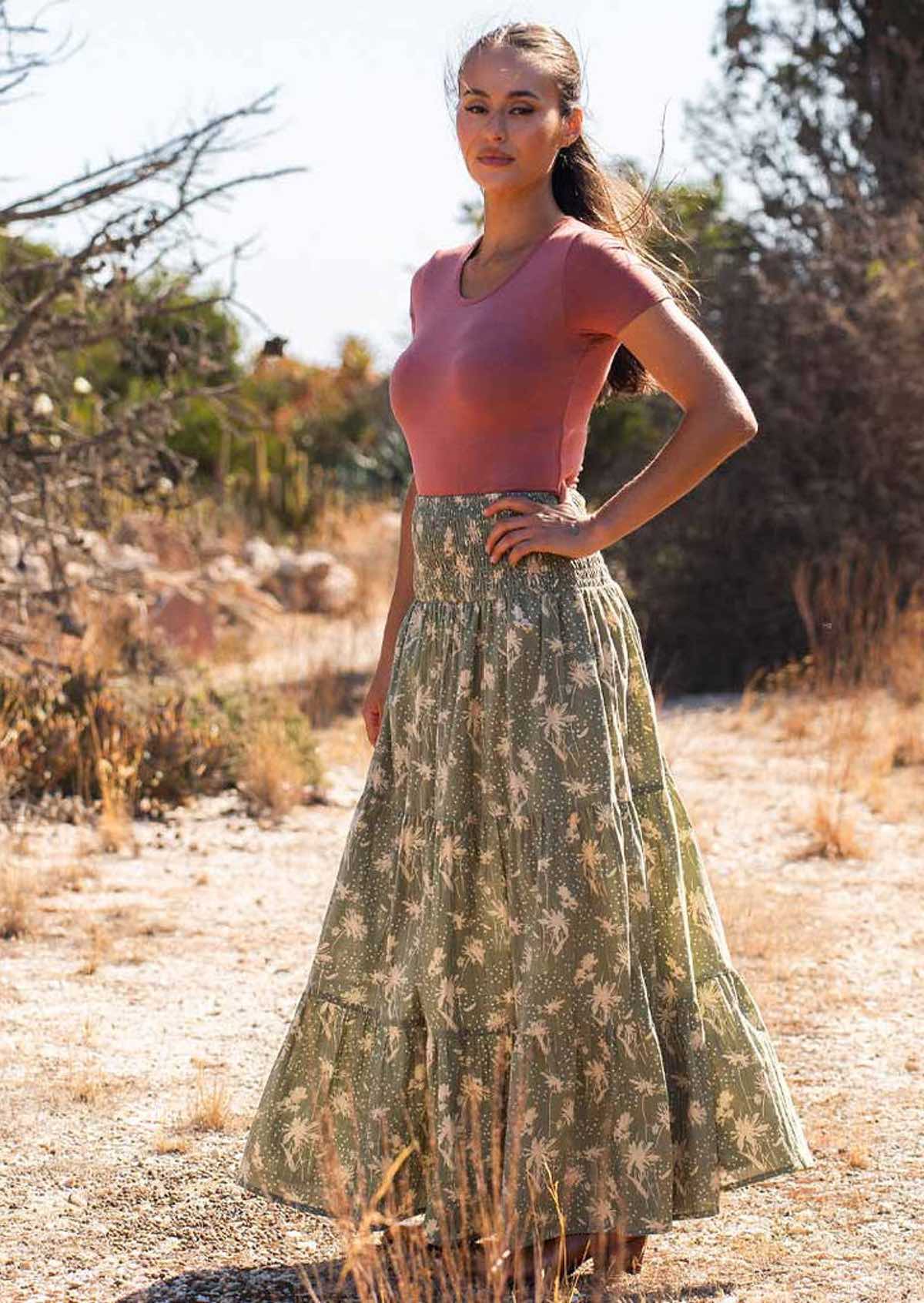 Woman stands with hand on hip wearing cotton maxi skirt paired with dusty rose stretch rayon top