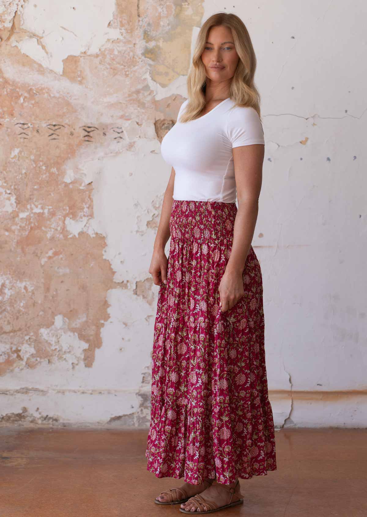 Woman stands sideways in cotton maxi skirt in floral print with white stretch rayon top