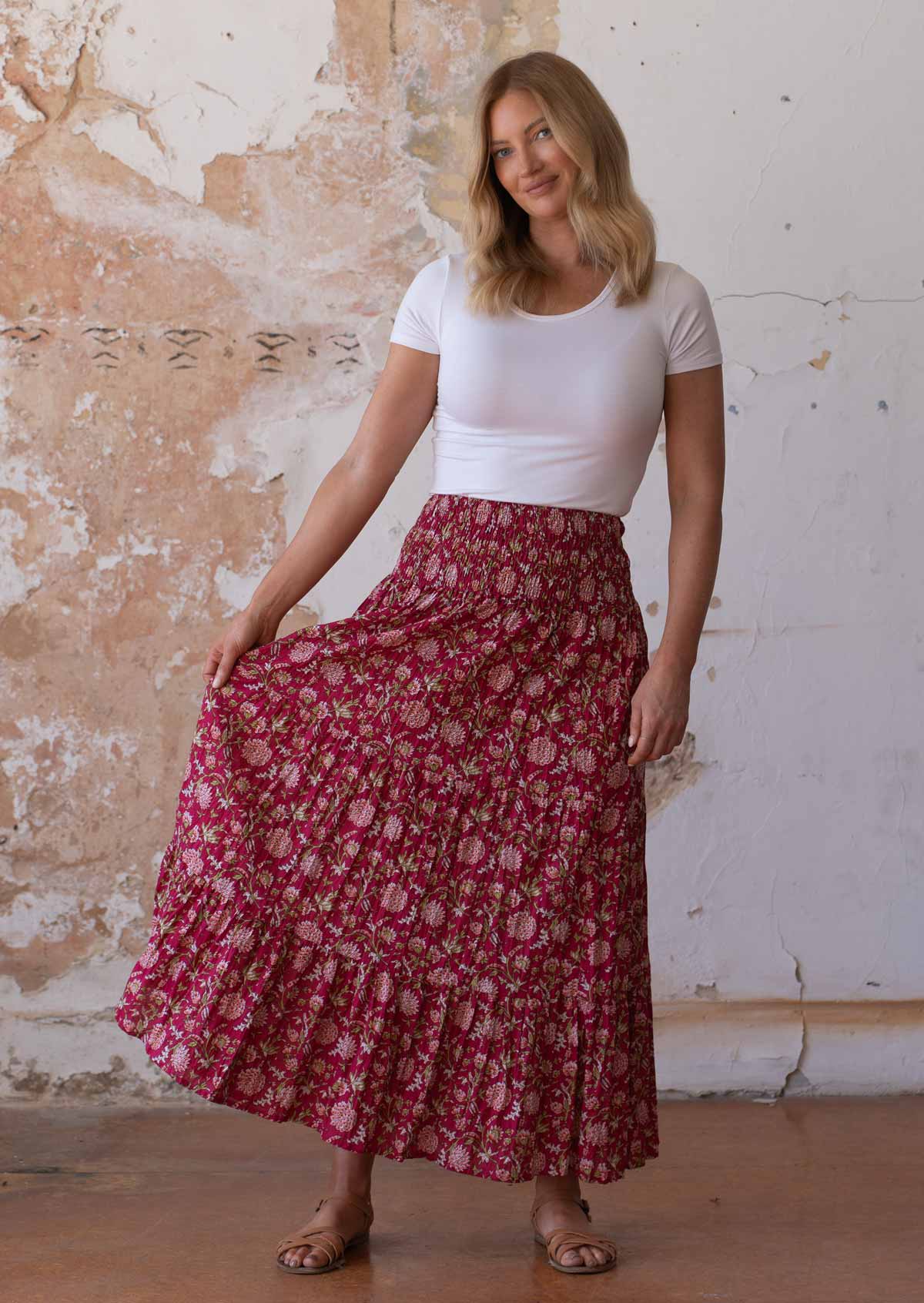 Woman holds side of cotton maxi skirt out, showing the volume of fabric in the tiers