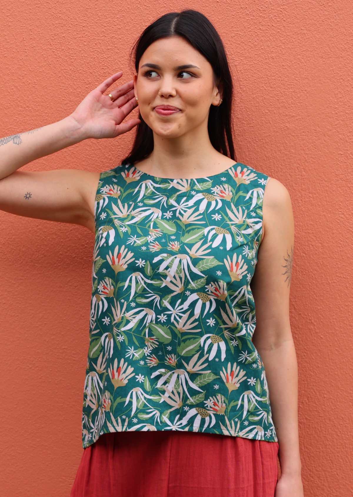 Model poses in sleeveless cotton top with high round neckline, in green based floral print