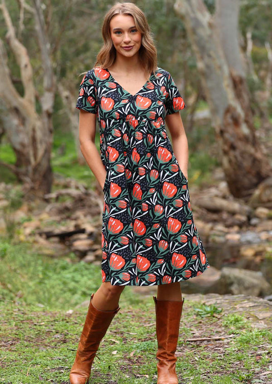 Model poses in cotton over the knee length dress in botanical print on black base