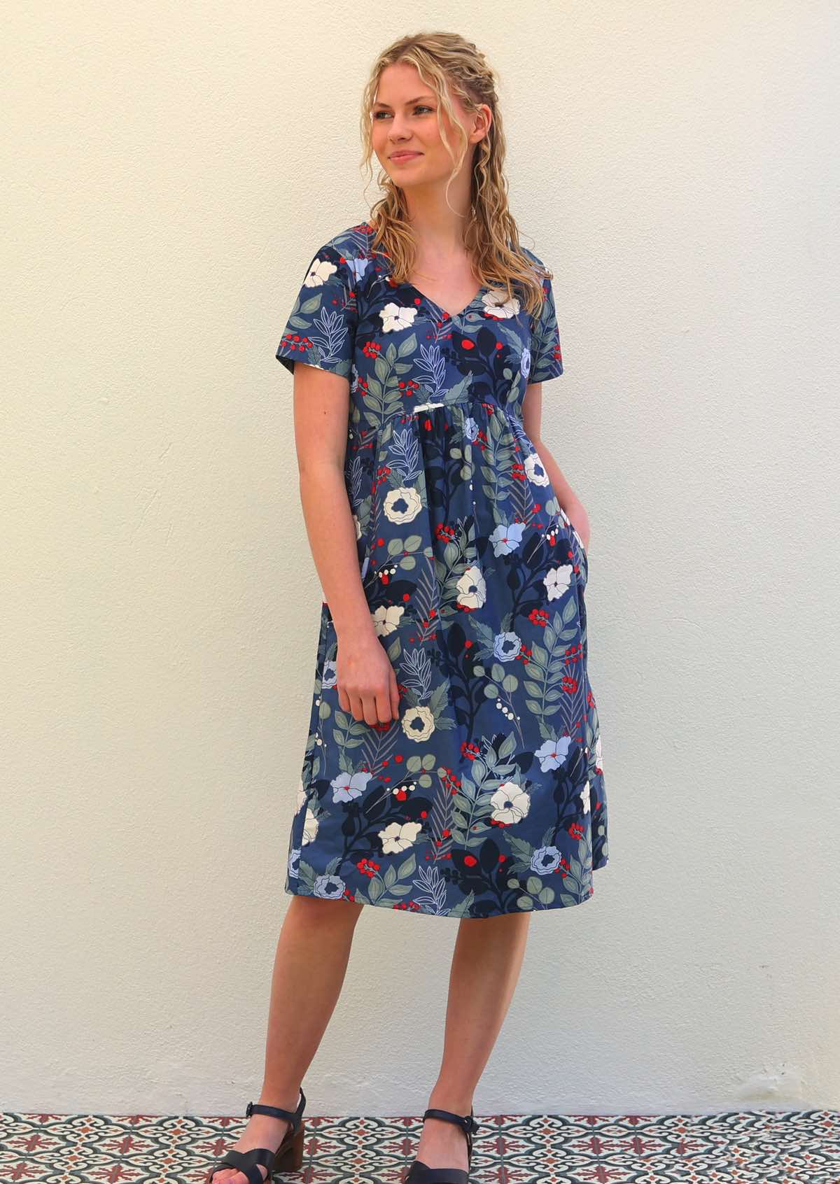 Woman wears cotton over knee length dress in bold blue floral print