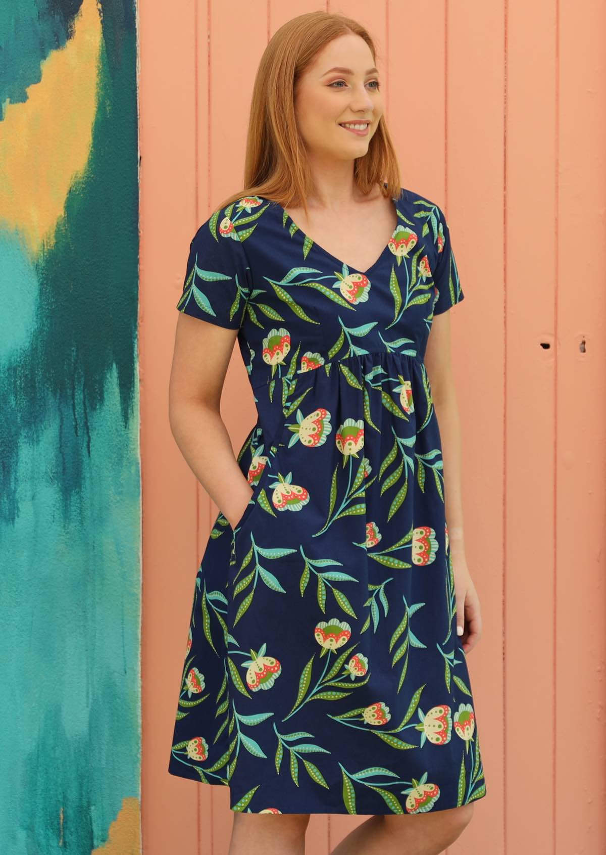 Red haired woman in navy blue floral cotton dress with pockets and v neck line 