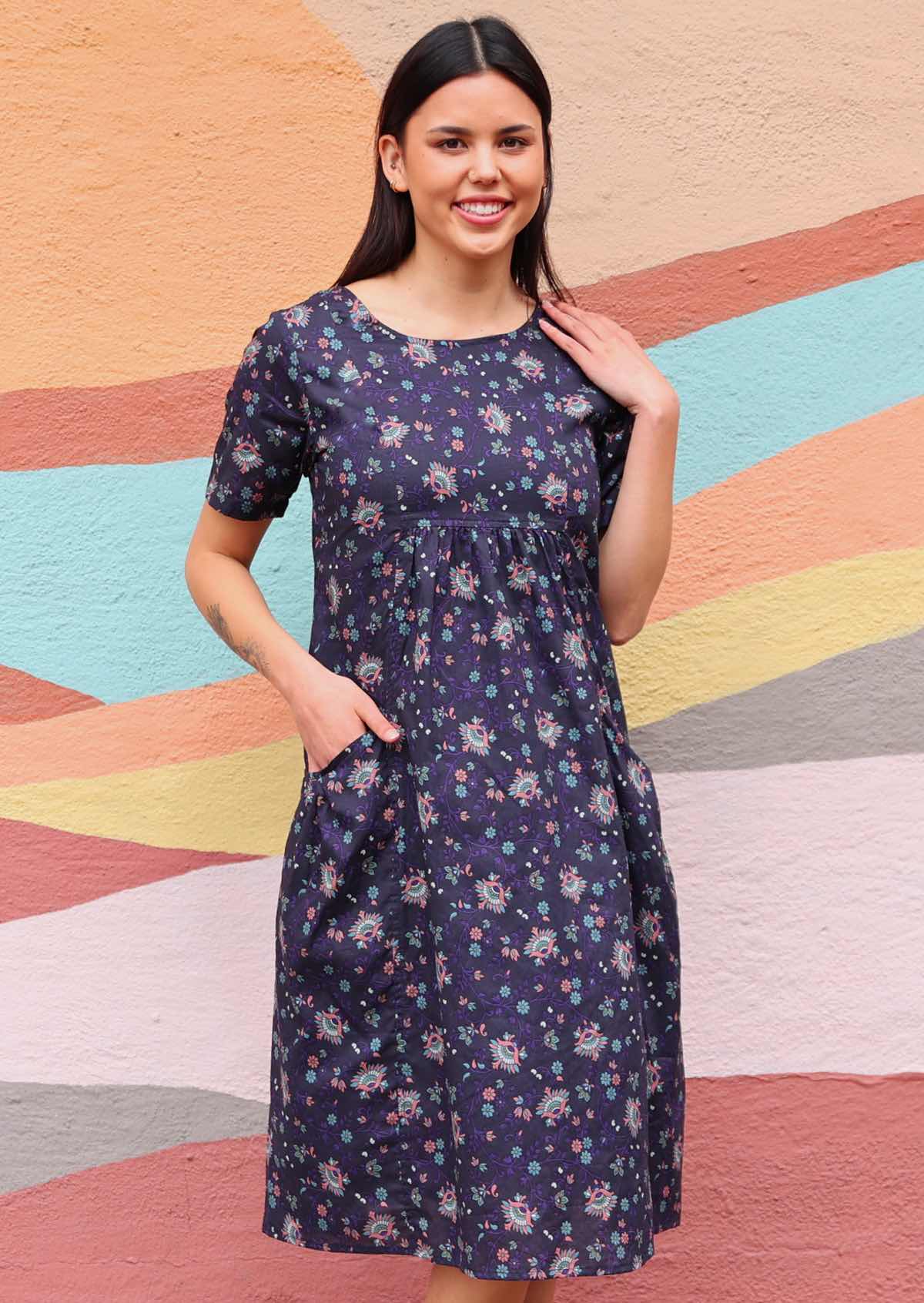 Woman in Indian print cotton dress with pockets in front of sun mural