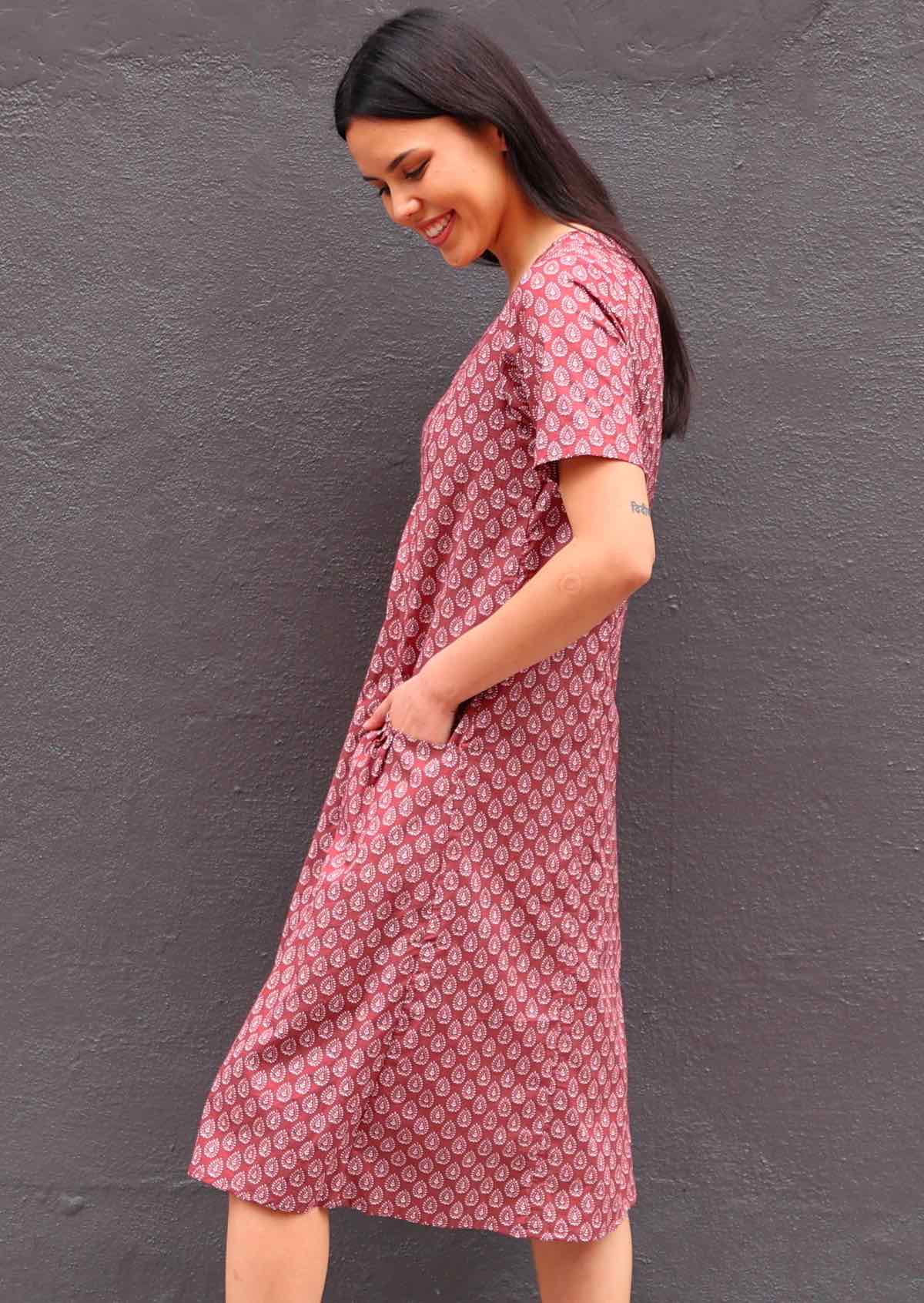 Model with her hand in pocket looking down and standing to the side wearing short sleeve cotton sundress