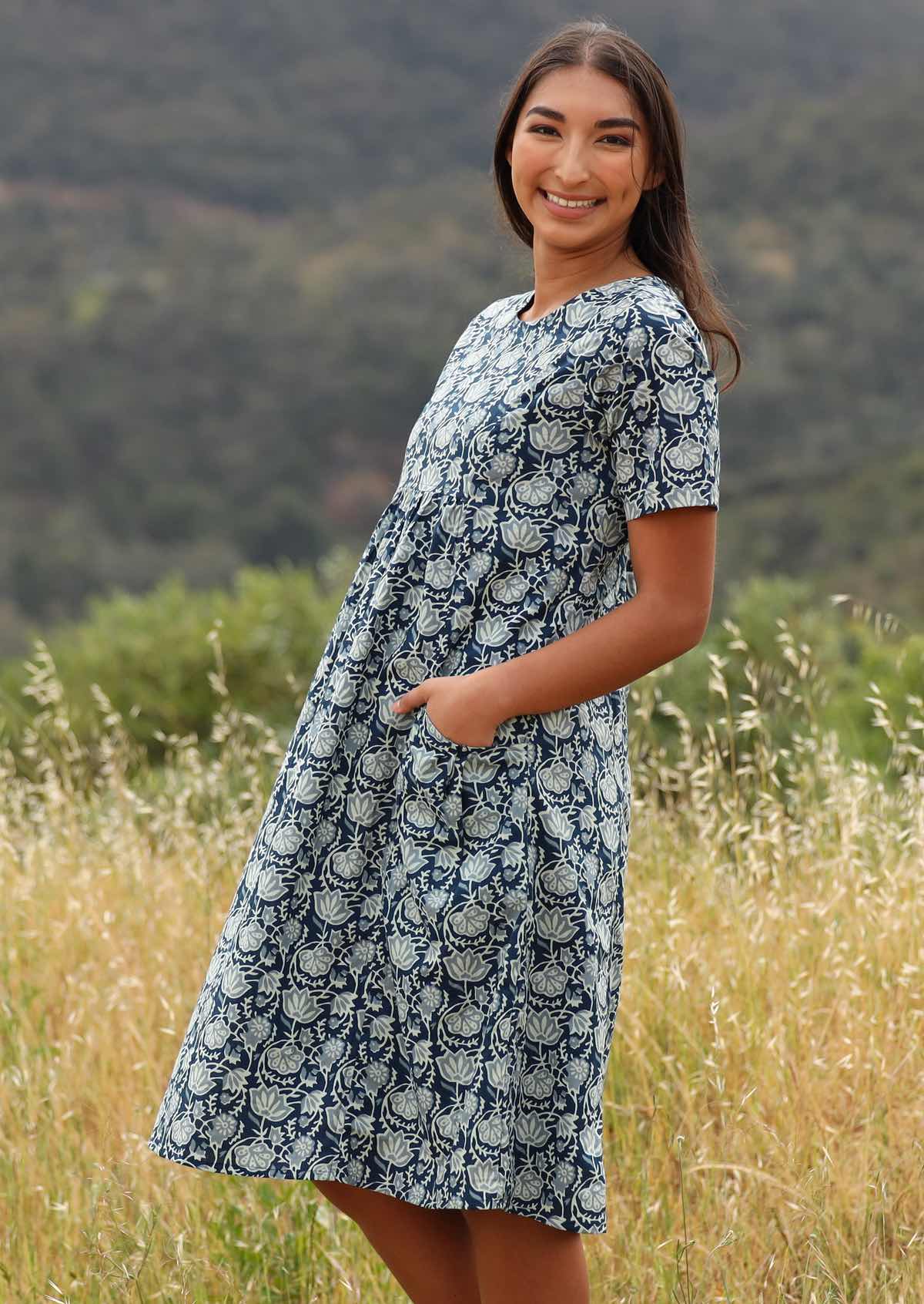 Smiling woman has her hands in the pockets of her dress. 