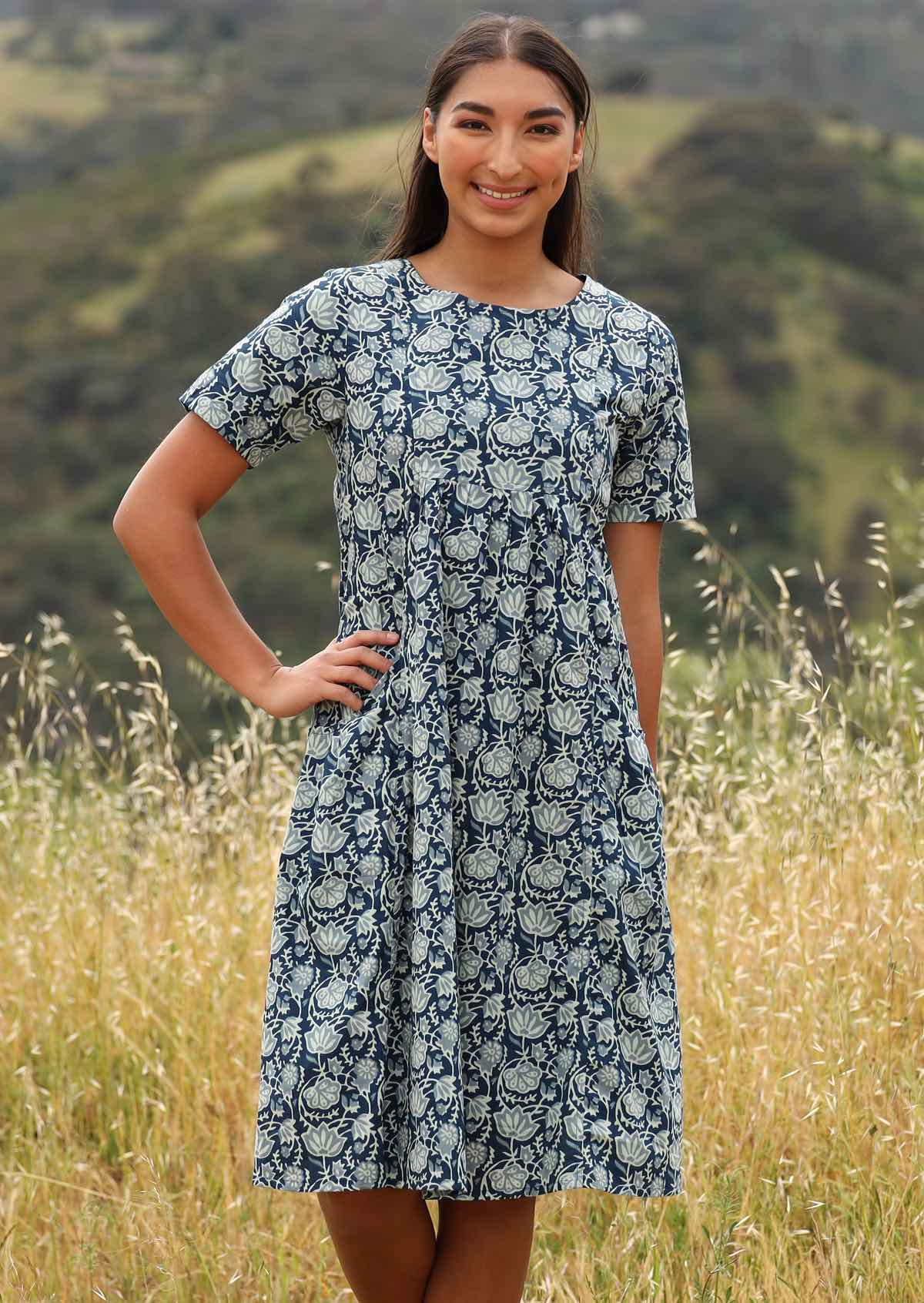 Model wears blue and white ornate floral print dress. 