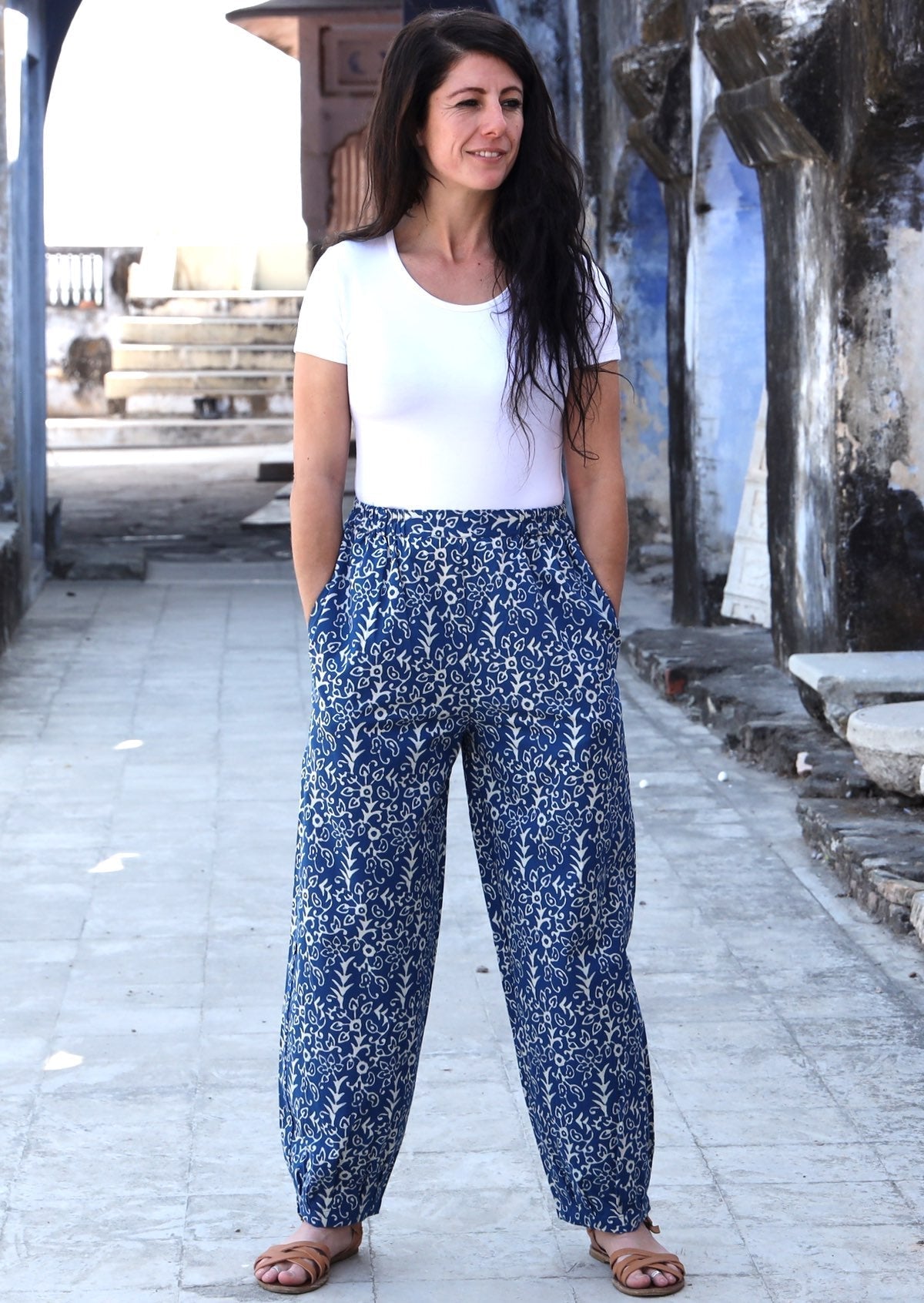 Woman standing with hands in pockets wearing blue Indian 100% cotton pants with white floral print