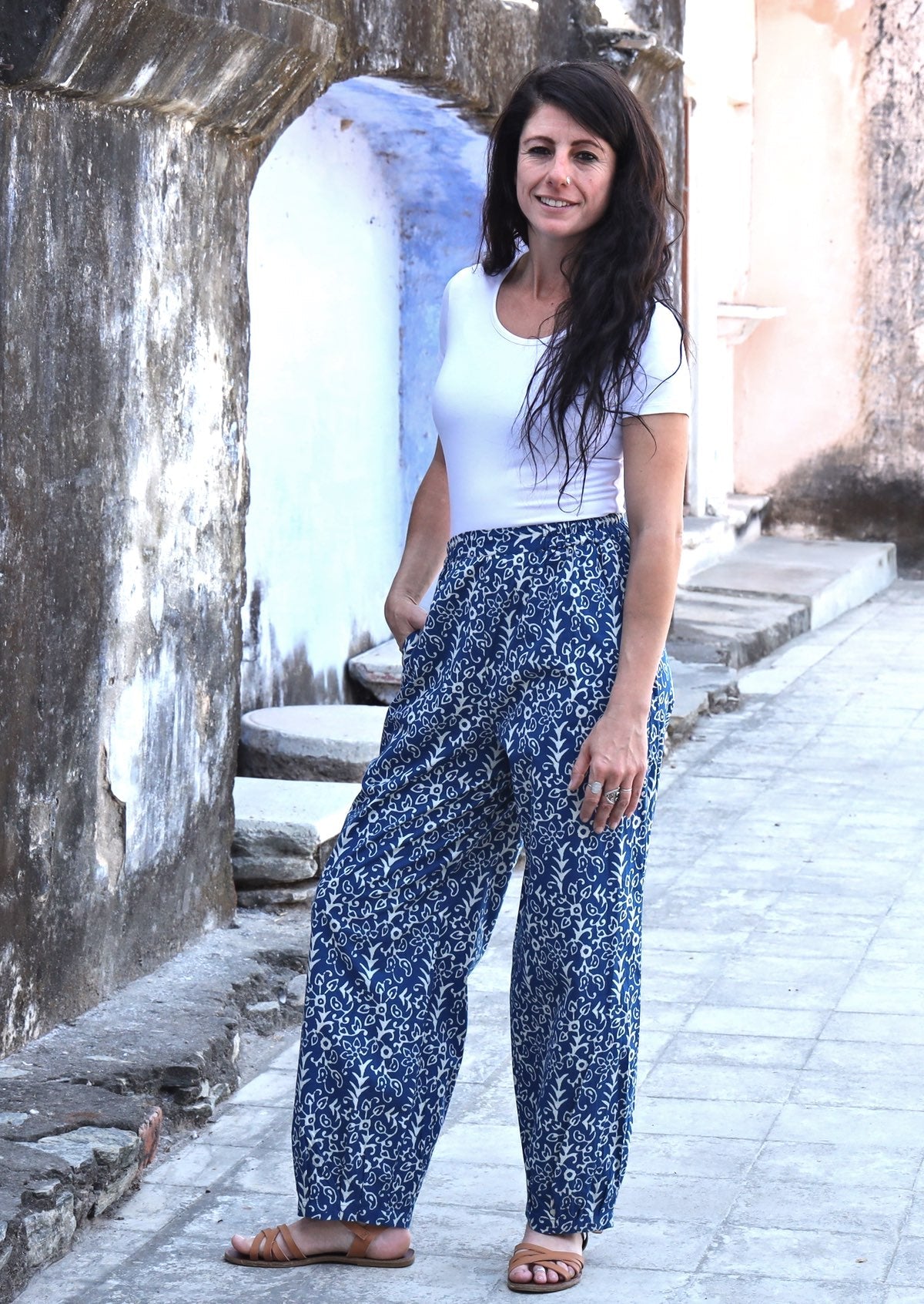 Woman modelling with one hand in pocket wearing blue Indian 100% cotton pants with white floral print