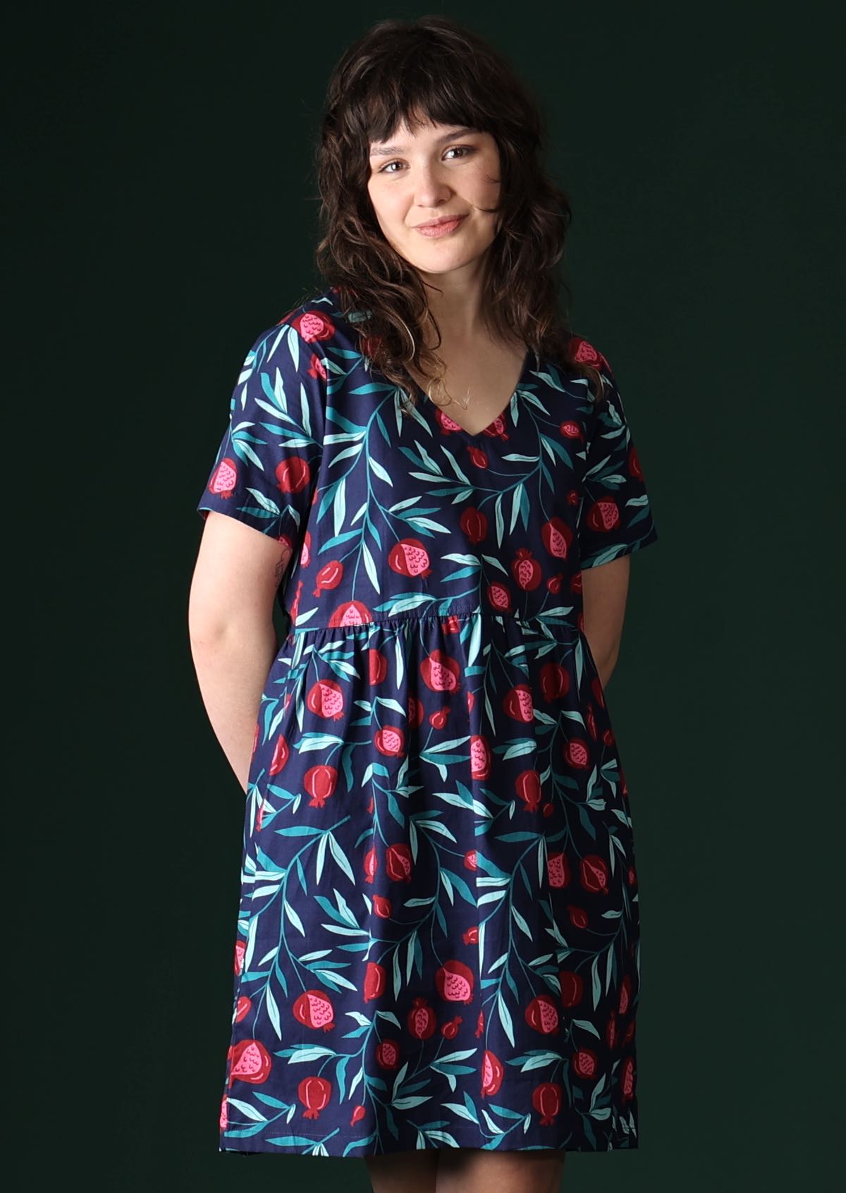 Model wears red fruit print dress on a navy base.