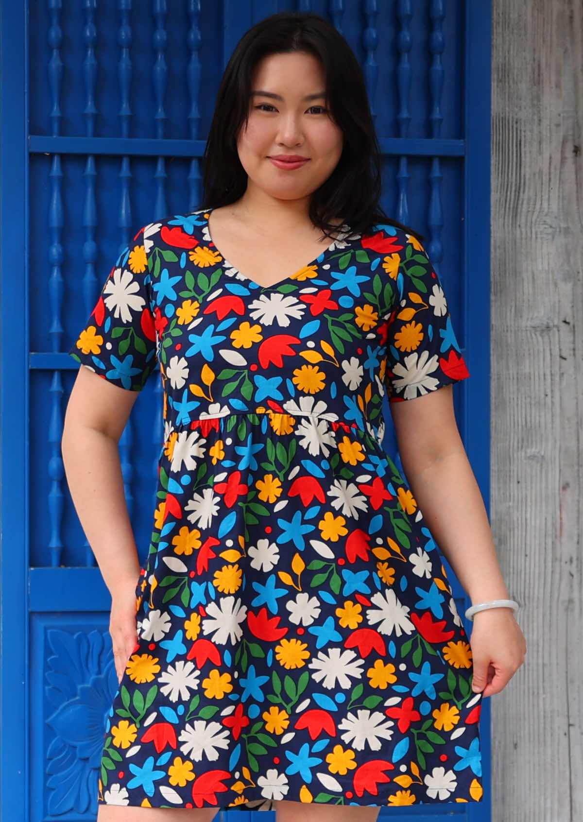 Woman stand in cotton above knee dress in fun bold floral print on dark blue base