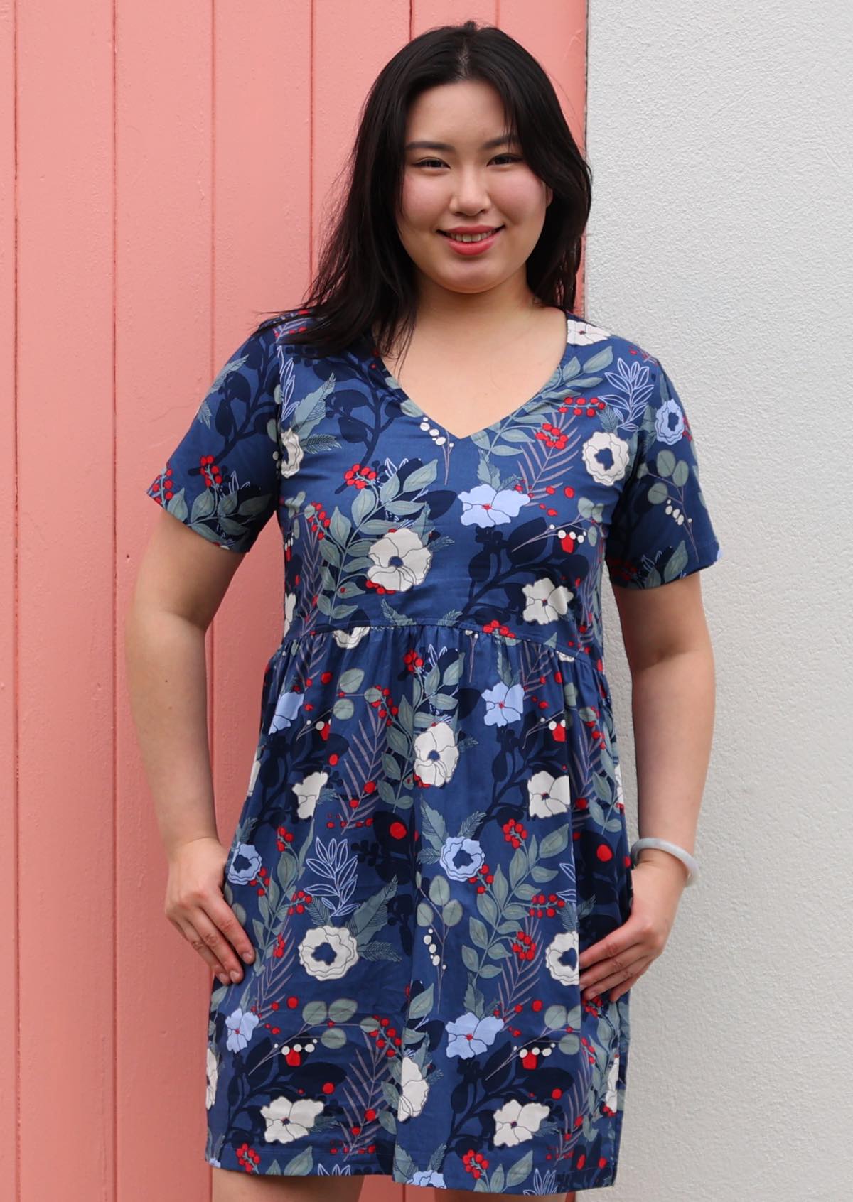 Woman wears above knee cotton relaxed fit dress with t-shirt sleeves and pockets in blue floral print