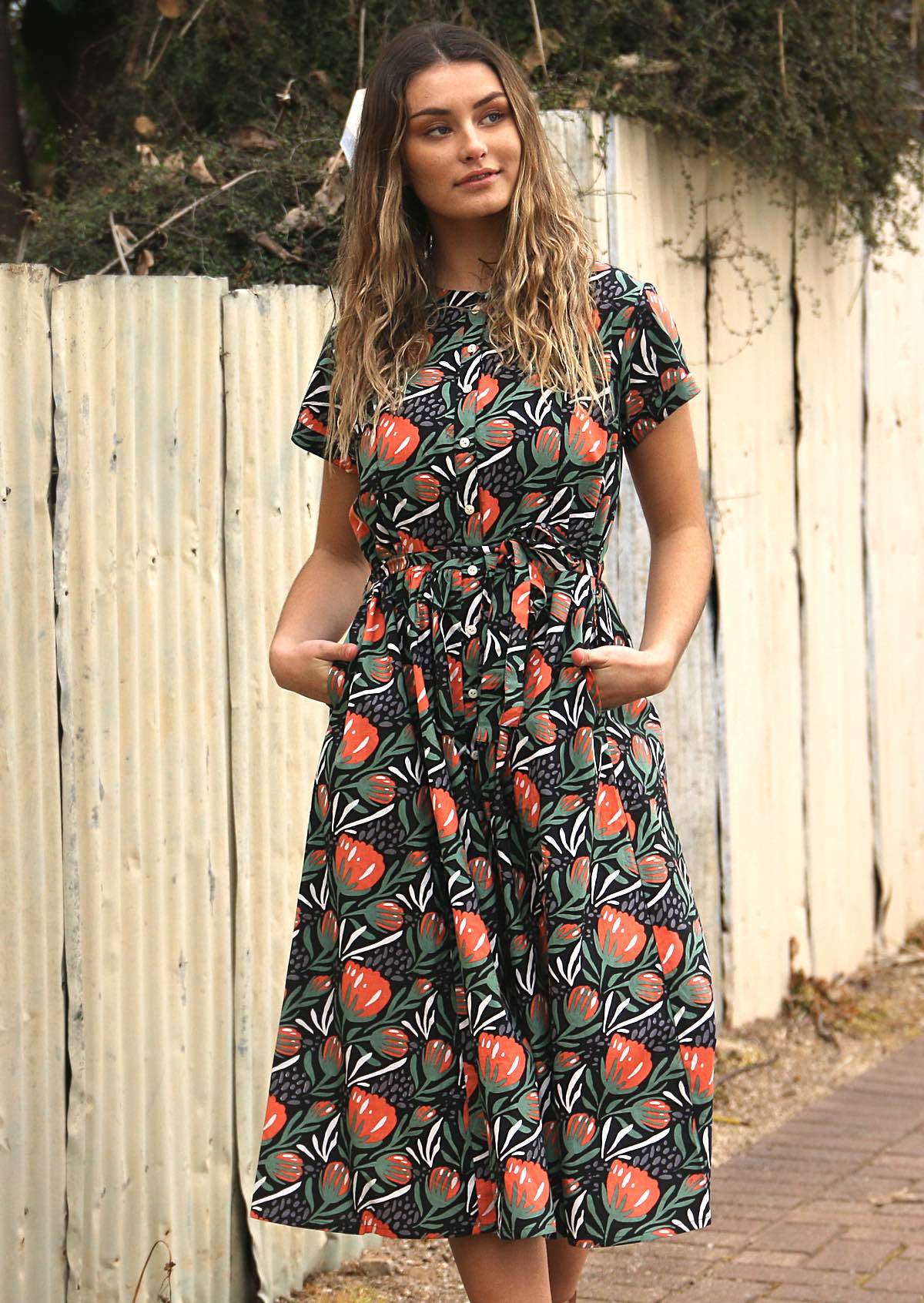 woman wearing floral print on black base cotton 1950's style midi length dress