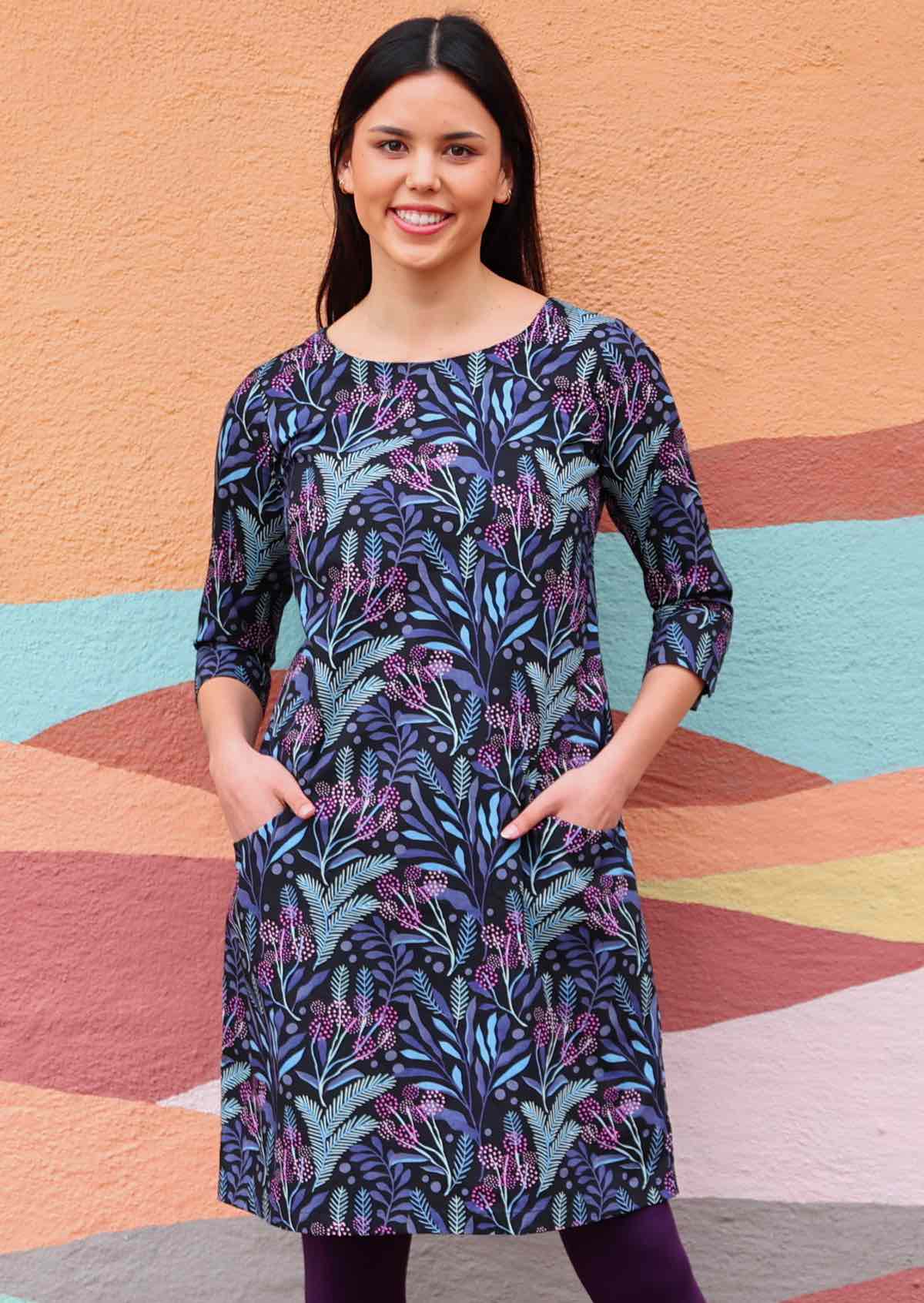 Long sleeve cotton dress in dark print with pockets awoman with dark hair