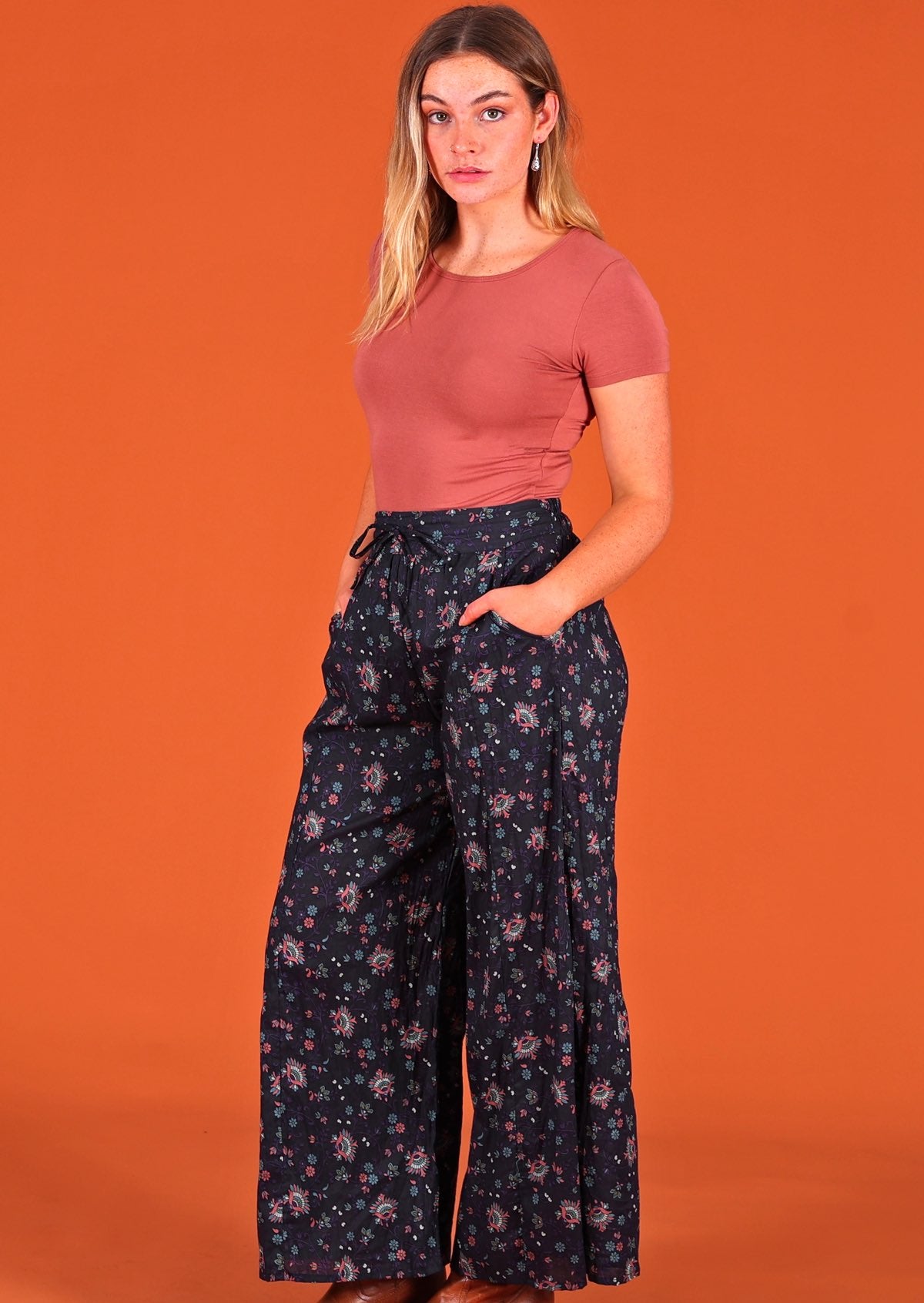 Model standing side on wearing Janis Pant Eventide 100 percent cotton wide legged women's palazzo with hands in pockets