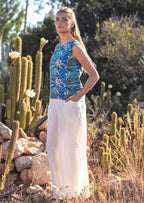 woman wearing wide legged white cotton pants and blue cotton top hand in pocket in front of cacti 