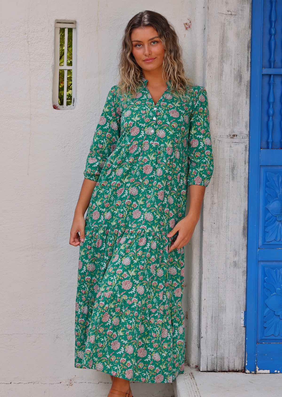 Model leaning against wooden frame wearing long sleeved 100 percent cotton maxi dress