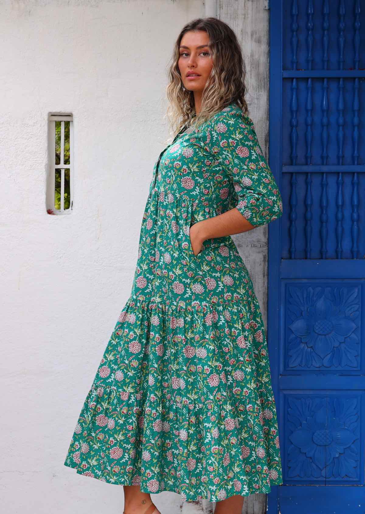 Model standing side on in front of white wall with hands in pockets wearing long sleeved 100 percent cotton maxi dress