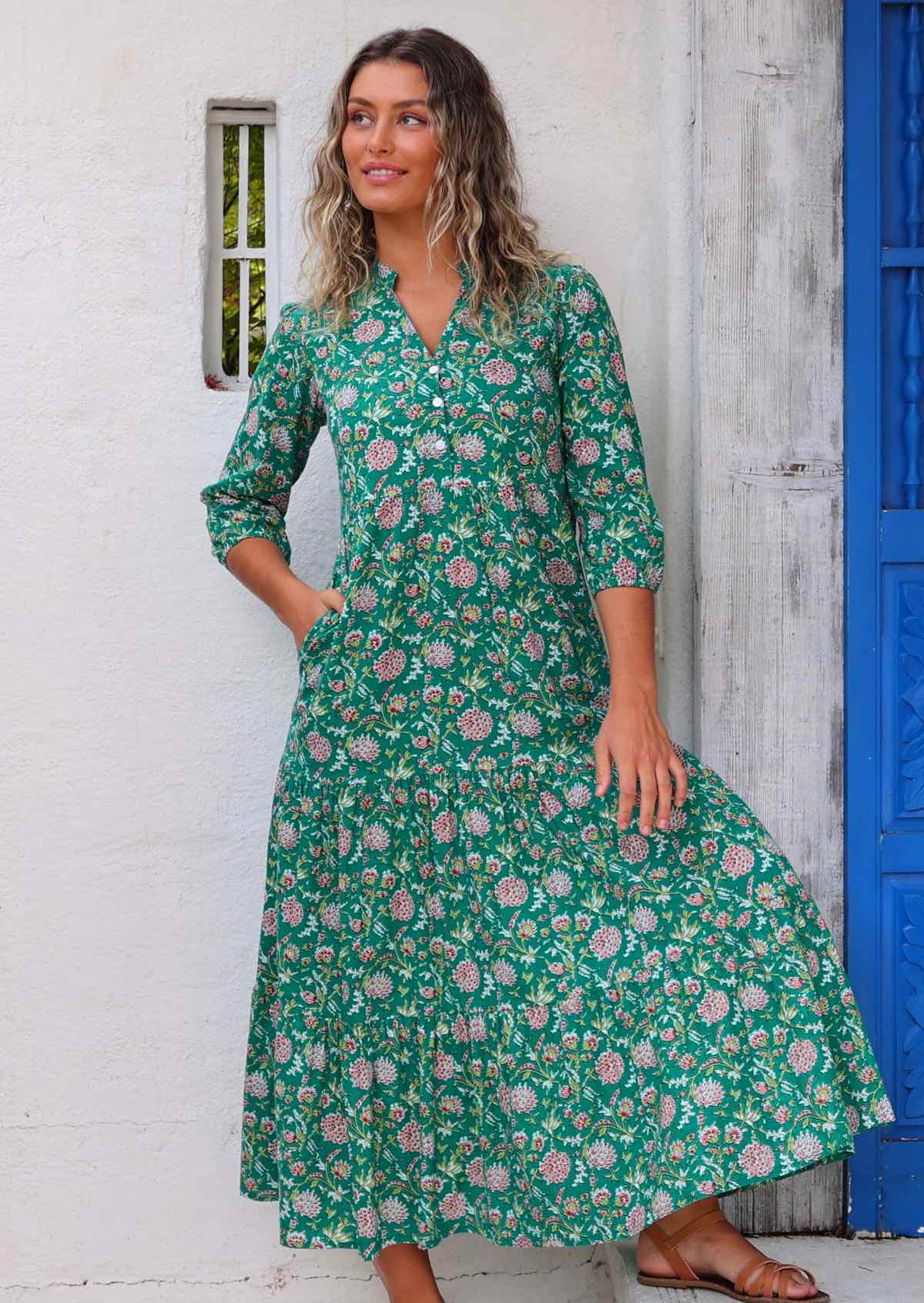 Model standing in front of white wall with one hand in pocket wearing long sleeved 100 percent cotton maxi dress