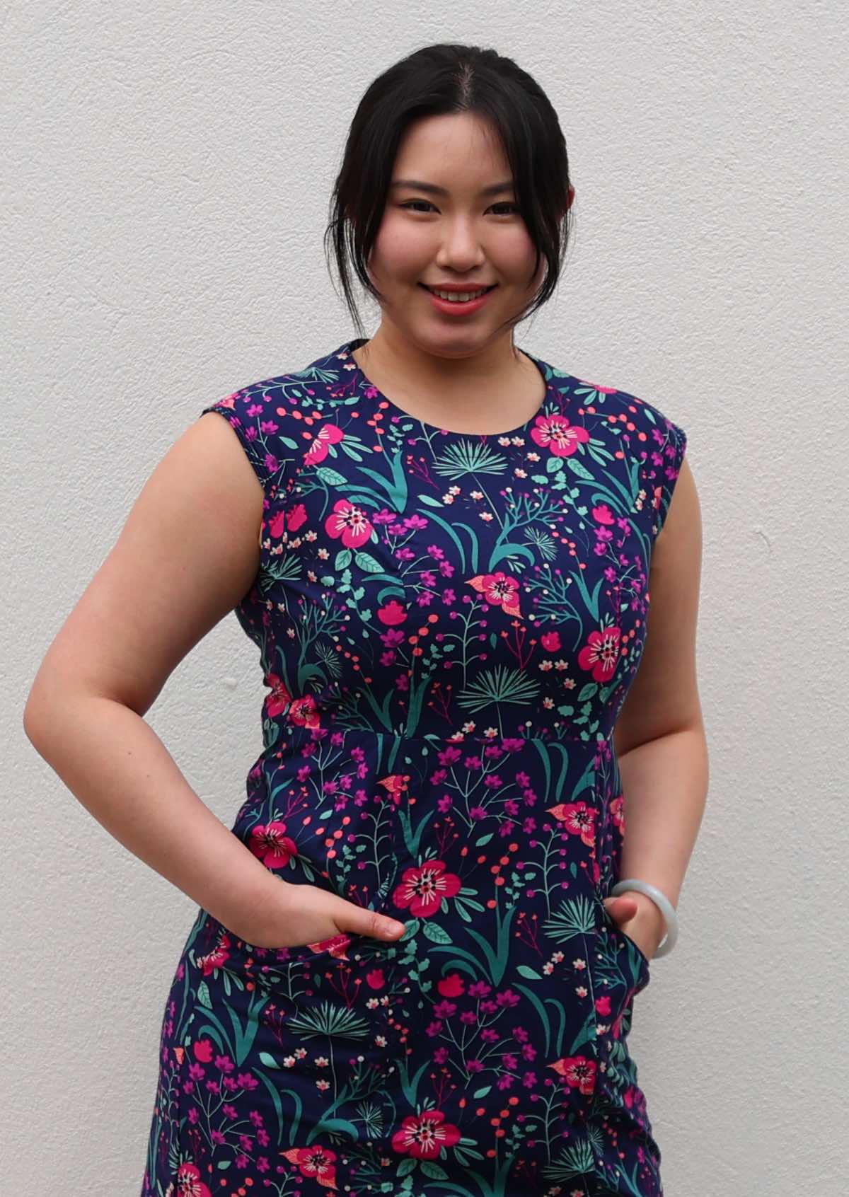 close up of Woman with dark hair in 100% navy cotton floral dress with hands in pockets