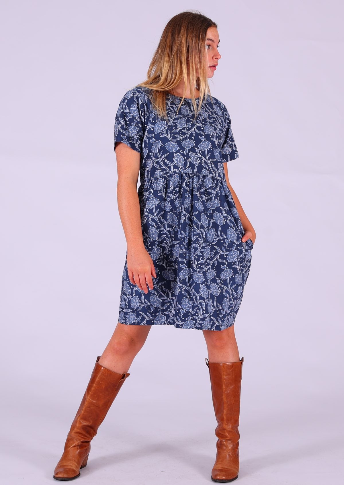 Model standing with hand in pocket wearing Mabel Dress Neela paired with tan leather boots