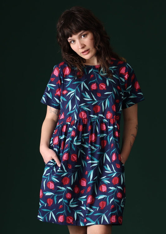 Model wears 100% cotton dress with a blue fruit print.