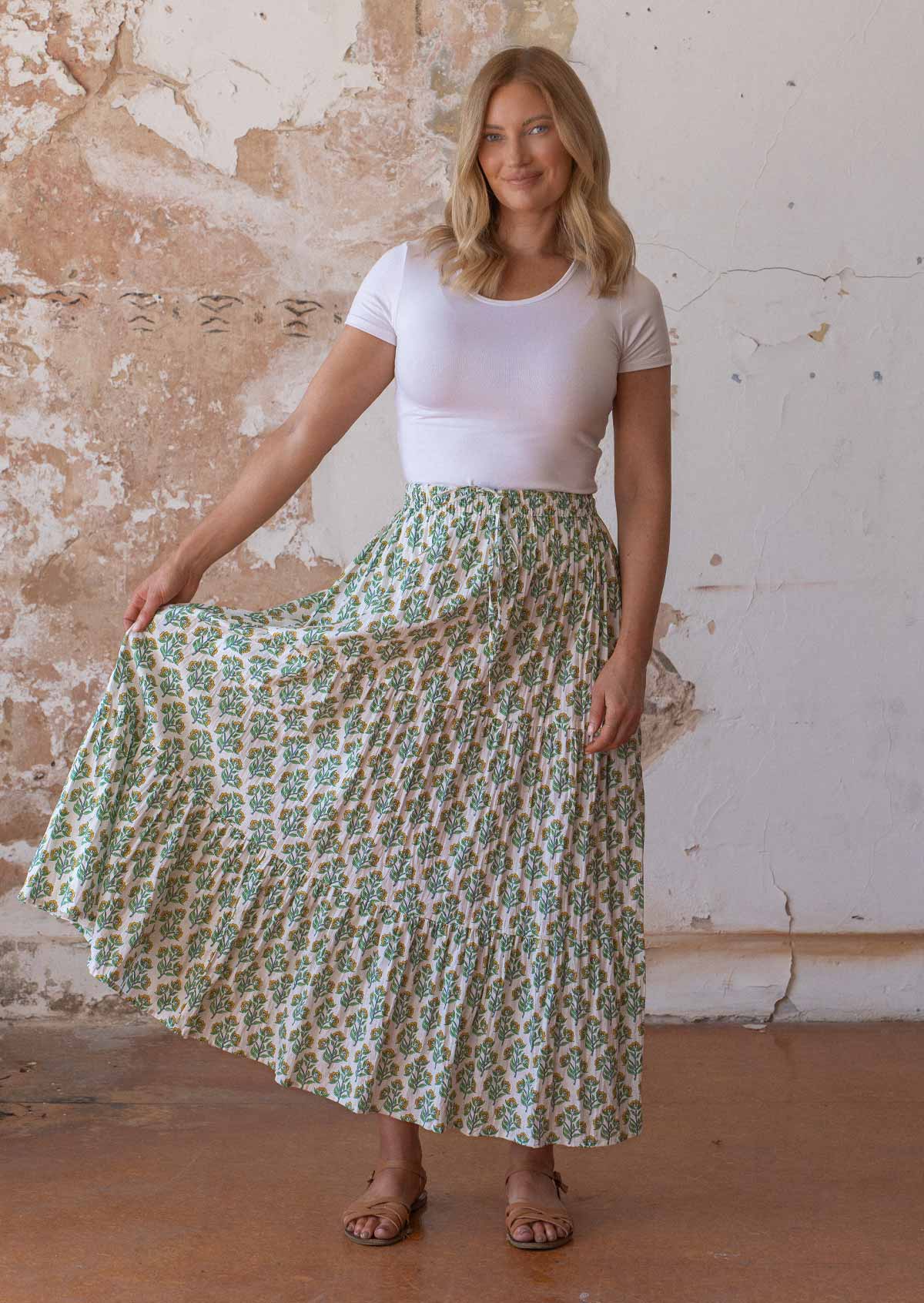 Woman holds cotton three tiered maxi skirt out with one hand