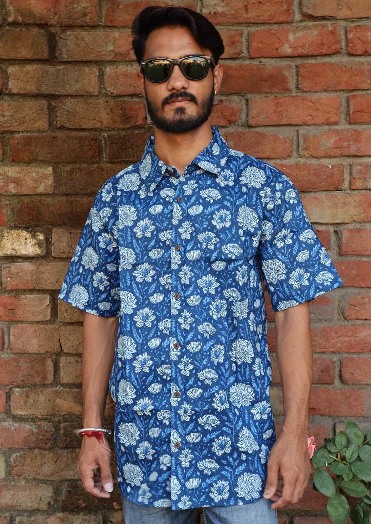 man standing in blue based floral print cotton short sleeve shirt with coconut buttons