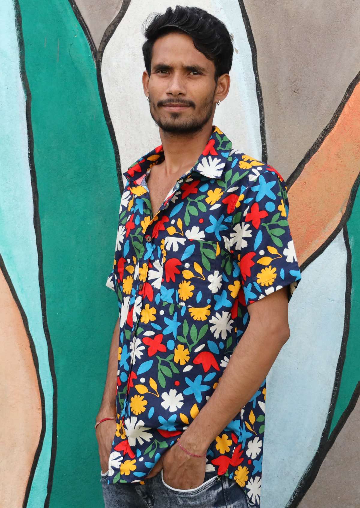 Man wears cotton relaxed fit button through shirt with bold floral print on a navy base