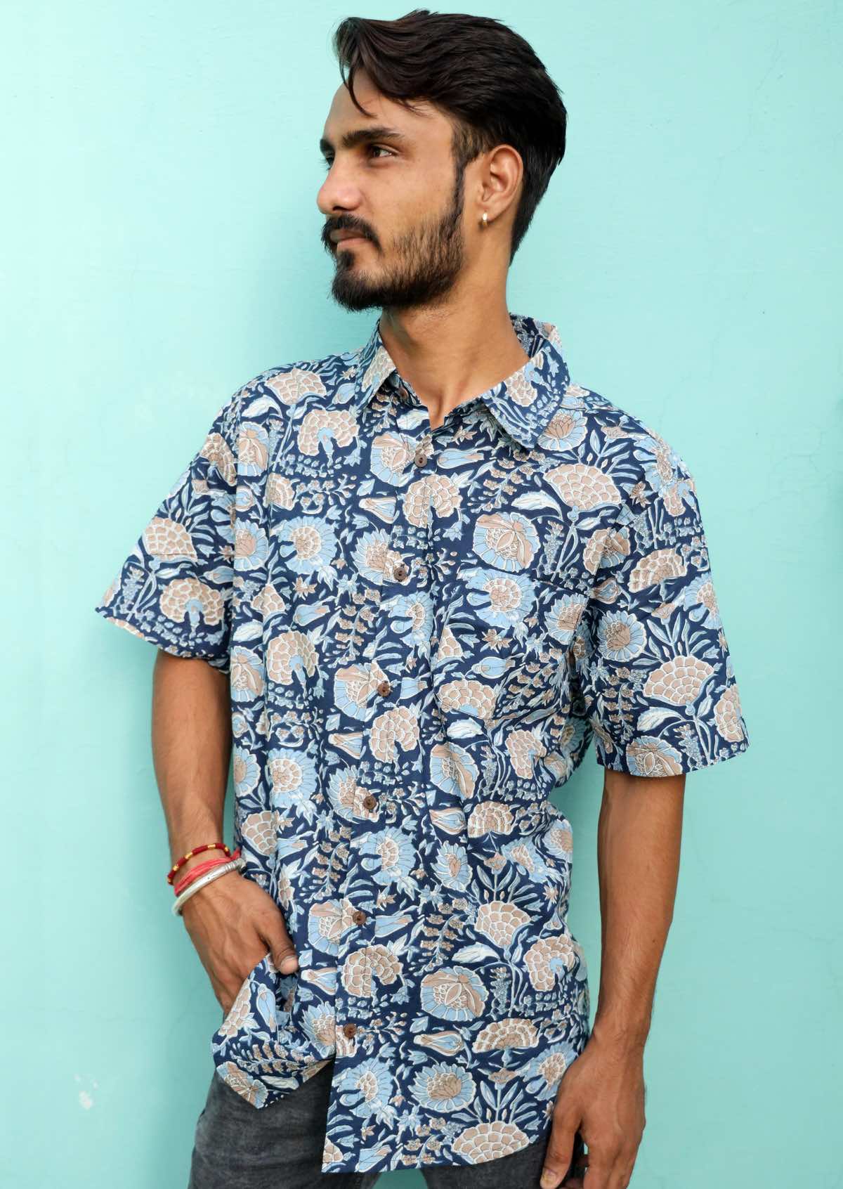 Man wearing light blue, taupe and white floral print on a navy blue base cotton short sleeve shirt