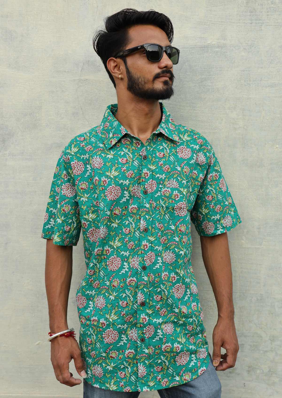 Man wears jade green based floral print cotton short sleeve shirt with coconut buttons