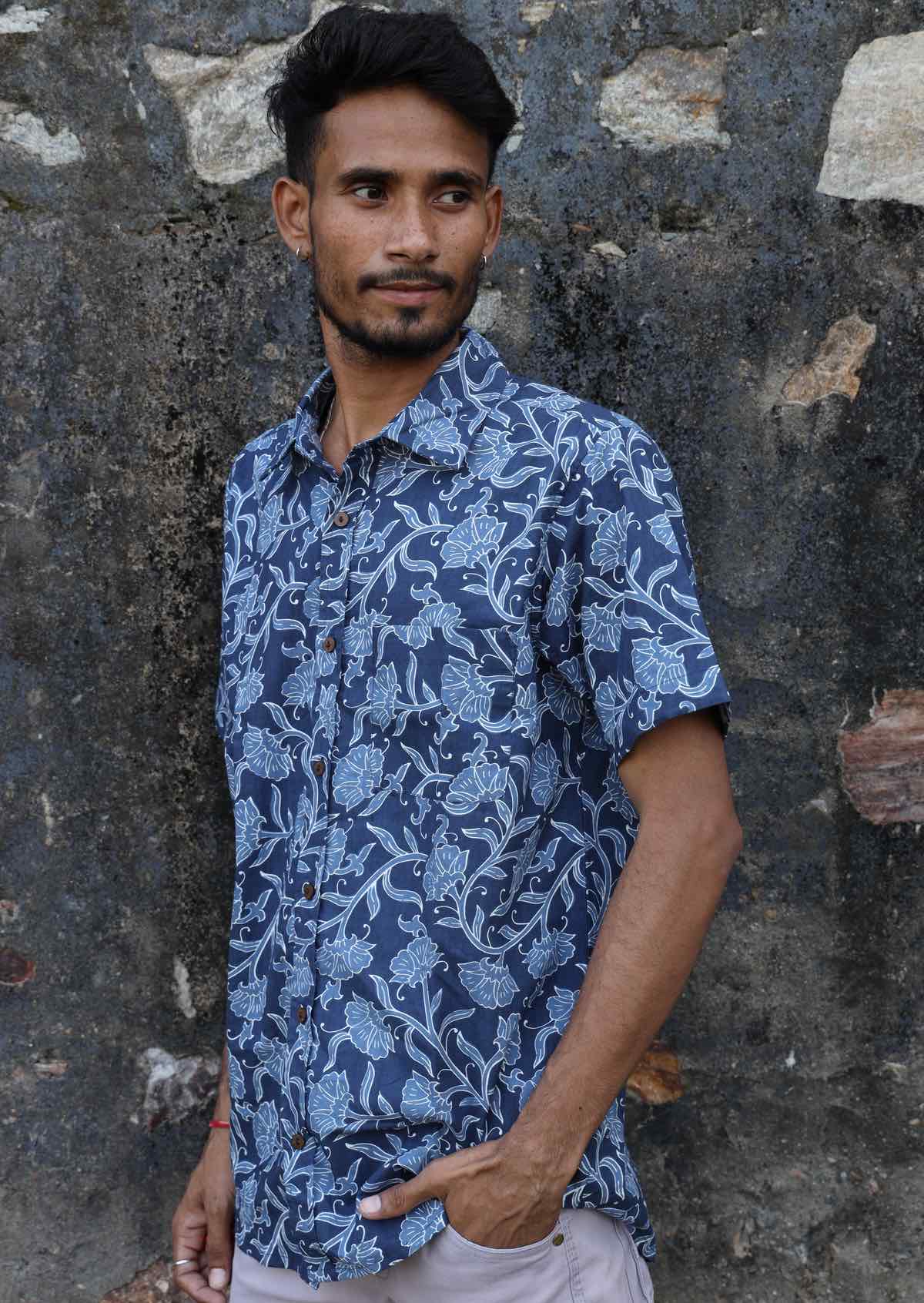 Man wears relaxed fit collared cotton shirt in blue hued floral print